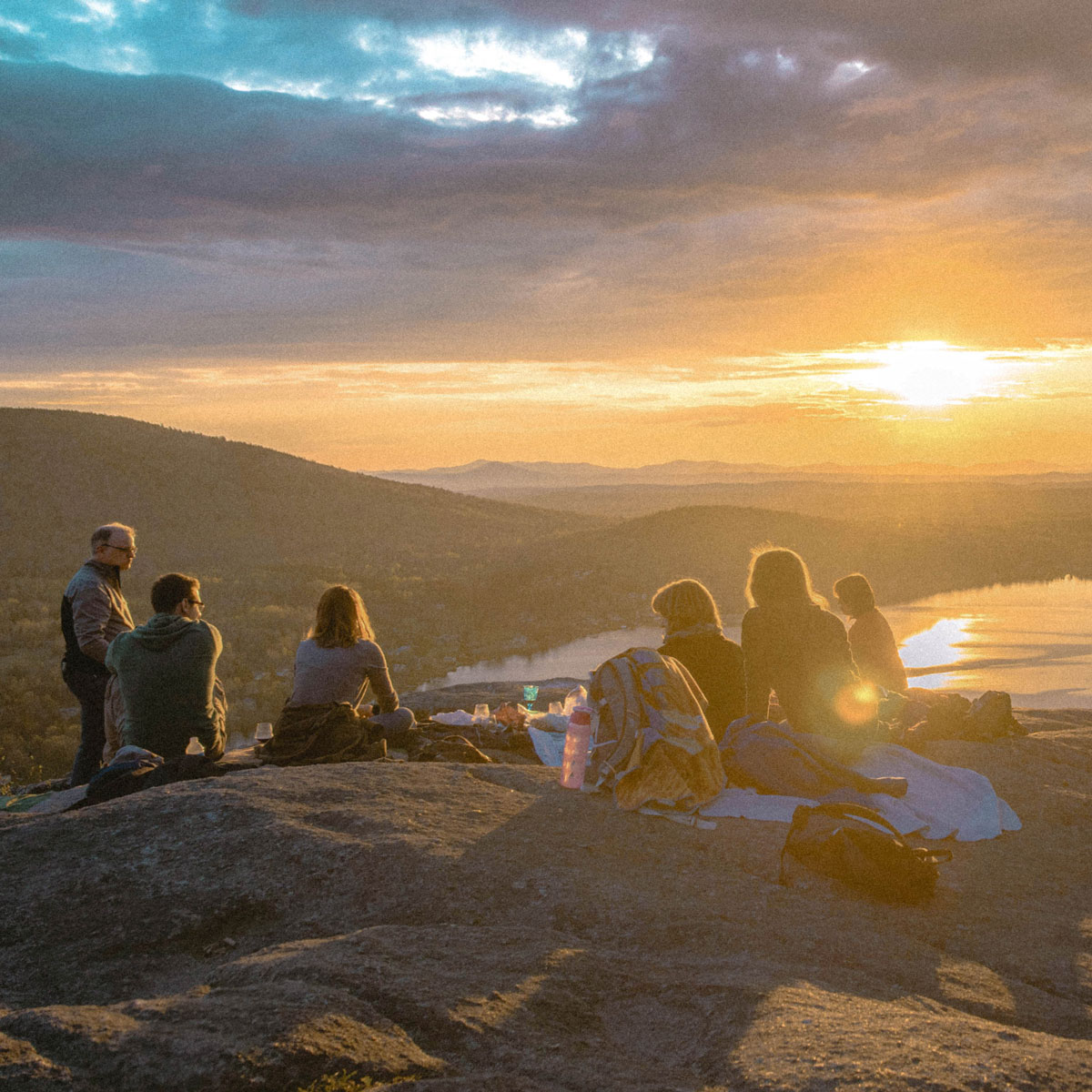 People watching the sunset together from a mountain rock