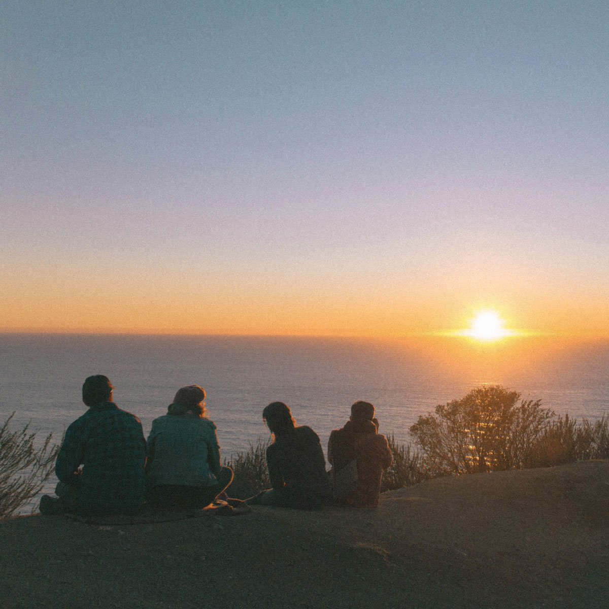 Group of 4 people watching the sunset and the sea