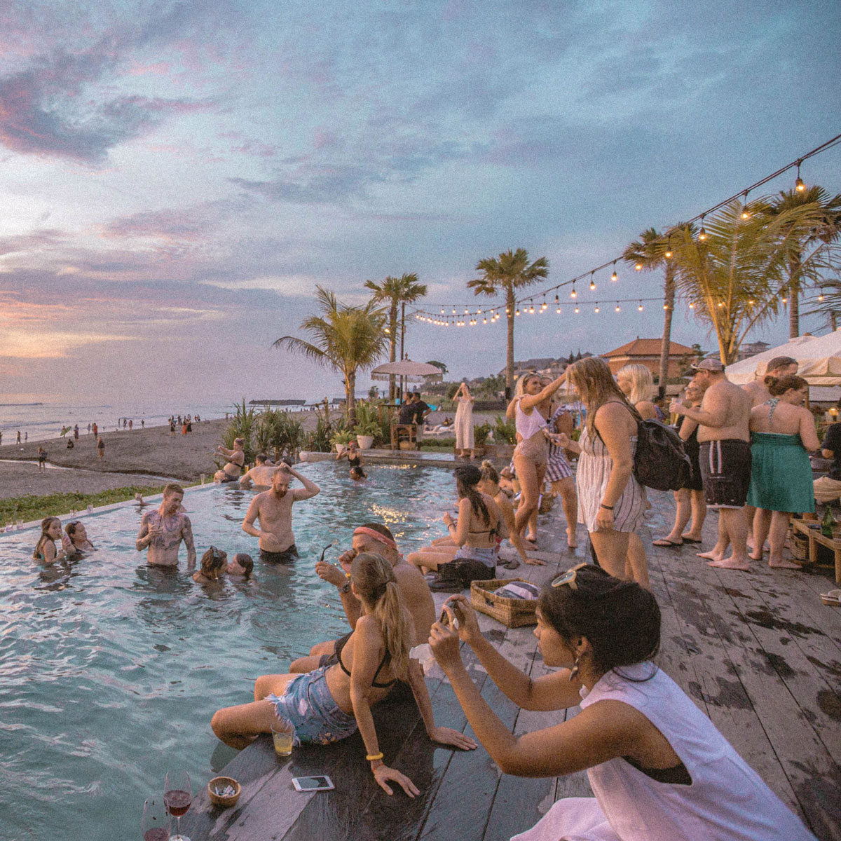 Vacationers relaxing at an outdoor restaurant with a pool, with the beach located right in front of the restaurant