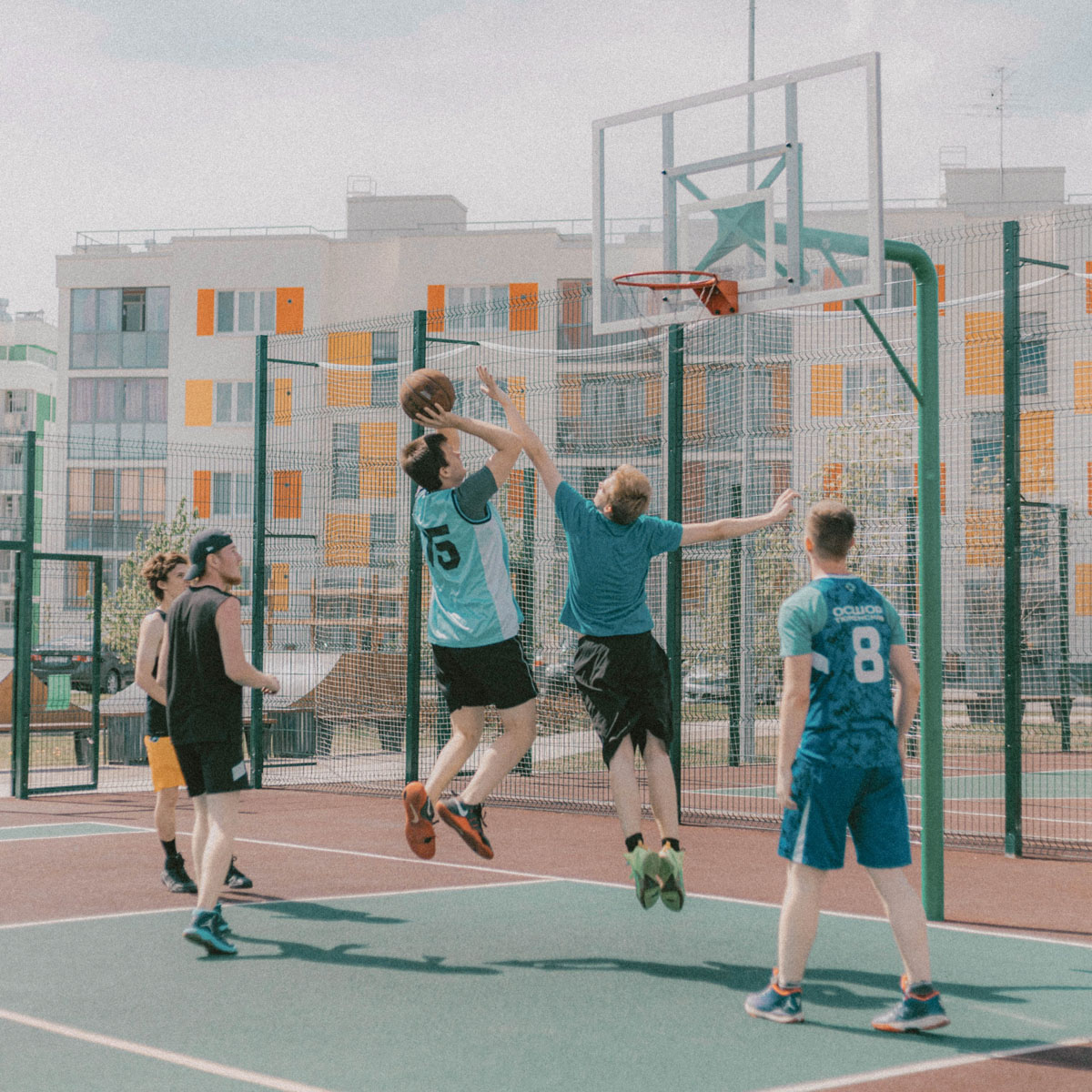 Group of people playing street basketball at a public basketball court